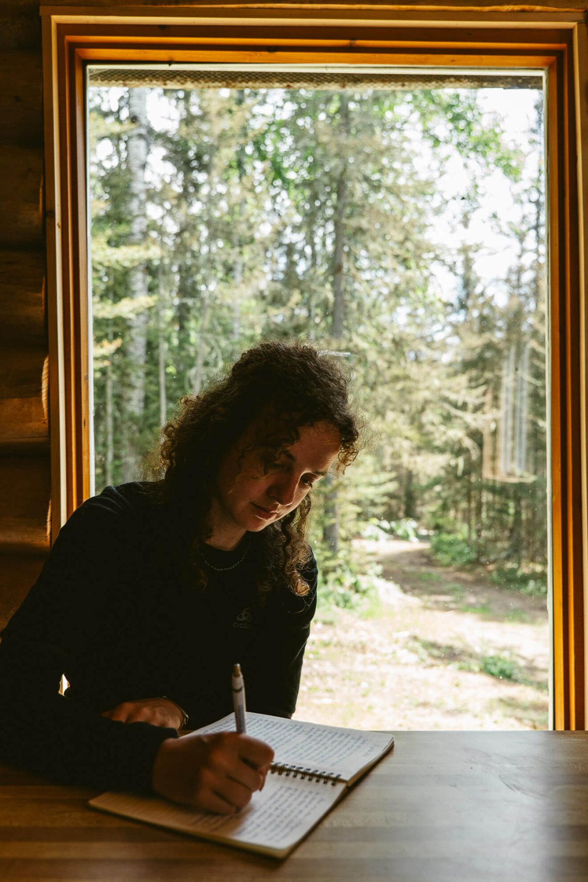 Femme qui écrit sur un carnet dans un refuge