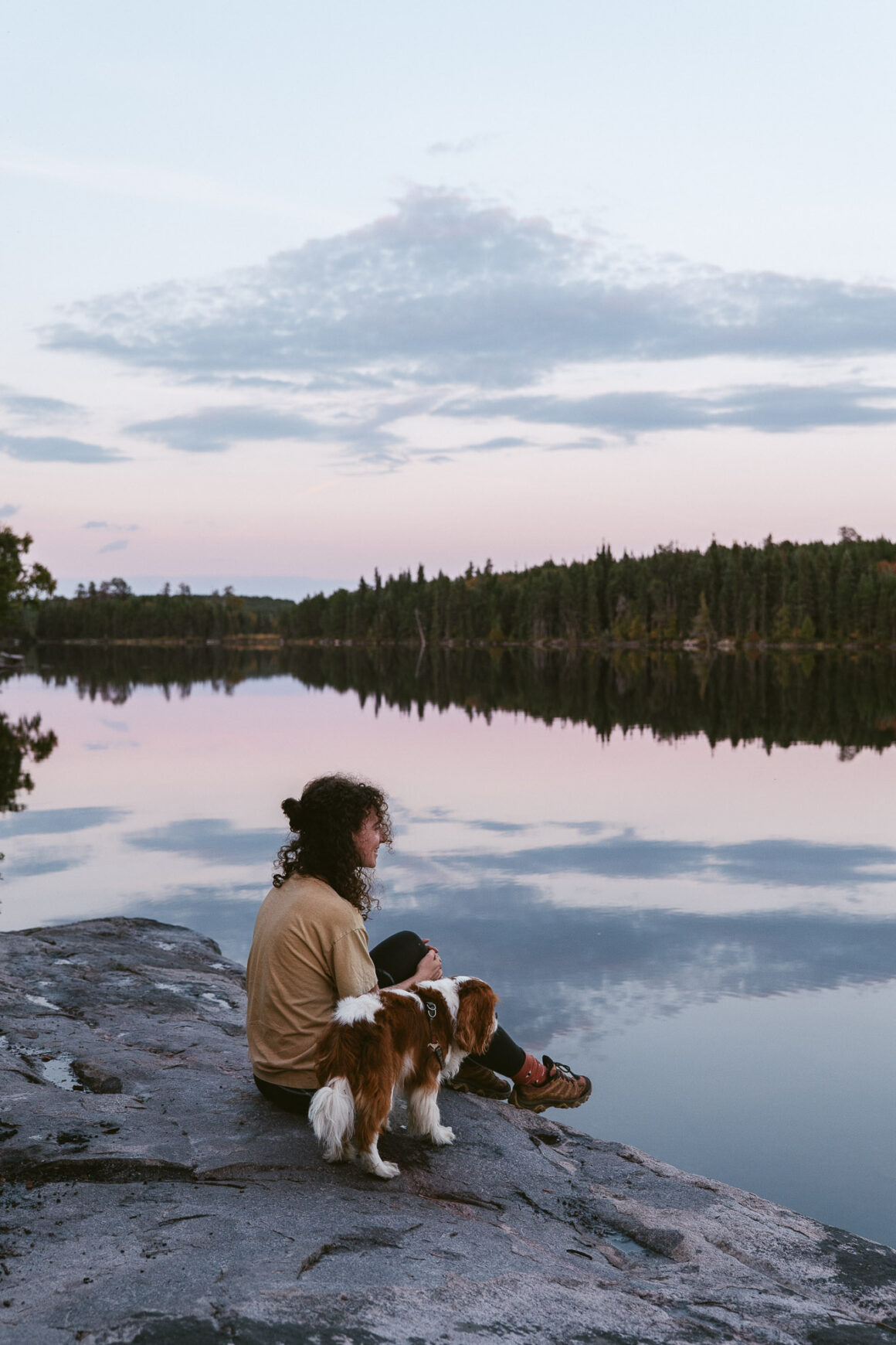 Personne avec son chien devant un lac au coucher du soleil