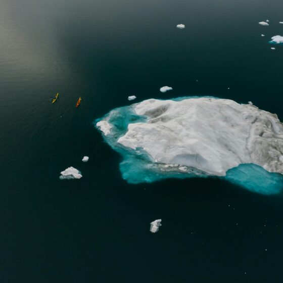 Vivre le changement climatique, des canoës près d'un bloc de glace