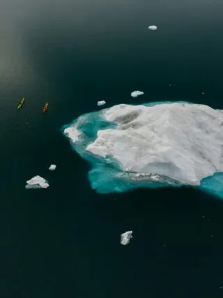 Vivre le changement climatique, des canoës près d'un bloc de glace